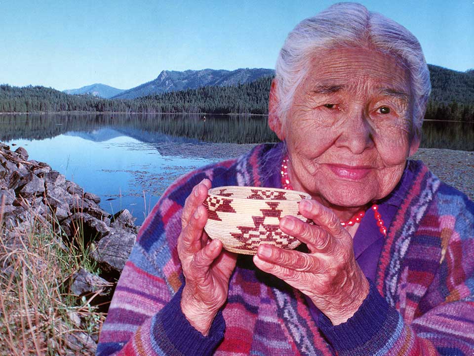 Elder greenville woman holding a traditional-style bowl and standing in front of a lake