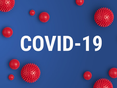 The word COVID-19 in white over a blue background, with red 3D-model representations of the virus floating around it