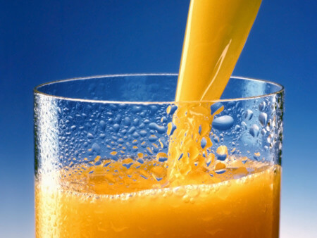 A glass of orange juice being poured